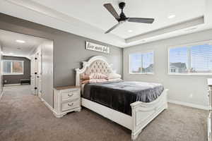 Bedroom featuring carpet, multiple windows, a raised ceiling, and recessed lighting