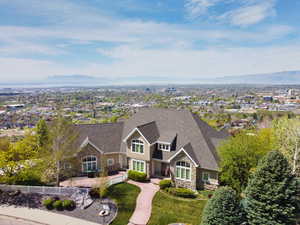 View of front facade featuring stone siding, a mountain view, roof with shingles, a front lawn, and a residential view