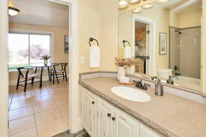 Bathroom featuring vanity, dark tile patterned flooring, and shower / bath combination