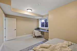 Bedroom featuring light colored carpet and built in study area