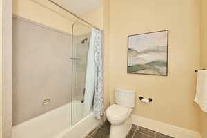Full bath featuring shower / bathtub combination with curtain and dark tile patterned floors