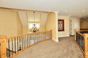 Hallway featuring a chandelier, carpet flooring, recessed lighting, crown molding, and an upstairs landing