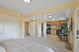 Bedroom with light colored carpet, light tile patterned floors, and freestanding refrigerator