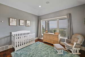 Bedroom featuring a crib, dark wood finished floors, and recessed lighting