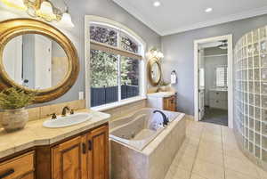 Bathroom with two vanities, light tile patterned flooring, ornamental molding, a tub with jets, and recessed lighting