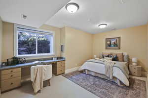 Bedroom featuring built in study area and light carpet