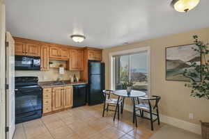 Kitchen with black appliances, light tile patterned floors, brown cabinetry, and open shelves