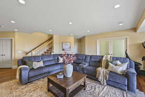 Living room with wood finished floors, recessed lighting, stairs, and french doors