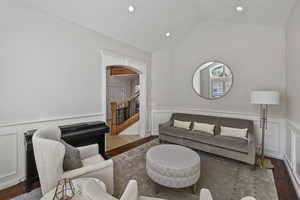 Living area with arched walkways, a decorative wall, a wainscoted wall, wood finished floors, and stairs