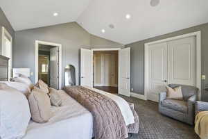 Carpeted bedroom featuring lofted ceiling, ensuite bath, and a closet