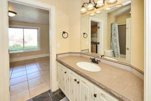 Bathroom featuring dark tile patterned floors, vanity, and curtained shower
