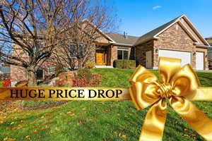 View of front of house with a front lawn, an attached garage, brick siding, stone siding, and a shingled roof