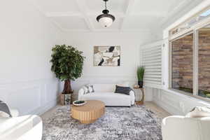 Sitting room with a decorative wall, carpet flooring, beam ceiling, coffered ceiling, and wainscoting
