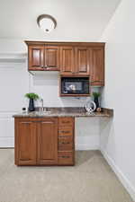 Kitchen with dark countertops, black microwave, and brown cabinets
