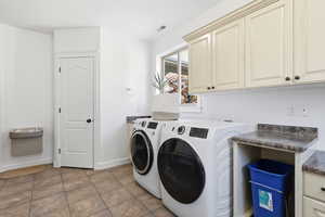 Washroom featuring independent washer and dryer, tile patterned floors, and cabinet space 1/2 bath and drinking fountain.