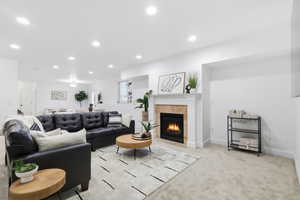 Living area with light colored carpet, a tile fireplace, and recessed lighting