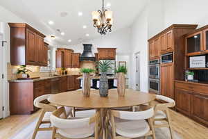 Dining room with light wood-style flooring, lofted ceiling, recessed lighting, and a chandelier