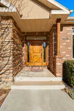 Entrance to property featuring brick siding and a porch