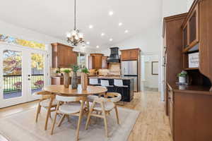 Dining space featuring recessed lighting, light wood-type flooring, a chandelier, french doors, and high vaulted ceiling