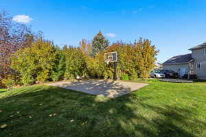 View of grassy yard featuring basketball hoop