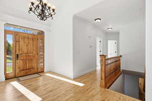 Foyer entrance featuring wood finished floors, a chandelier, and ornamental molding