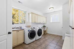 Laundry room featuring washer and dryer, cabinet space, and dark tile patterned floors