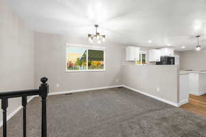 Unfurnished living room featuring light carpet, a chandelier, and recessed lighting