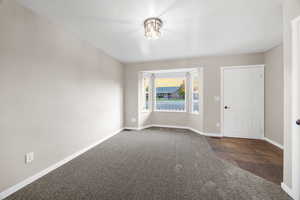 Empty room featuring dark colored carpet and baseboards