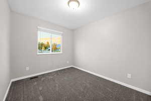 Spare room featuring dark carpet and a textured ceiling