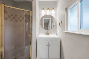 Full bath with vanity, a stall shower, and a textured wall