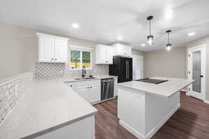 Kitchen featuring tasteful backsplash, white cabinetry, a center island, dark wood-type flooring, and recessed lighting
