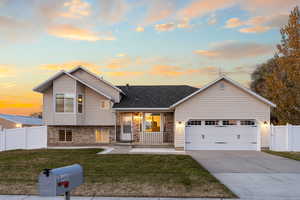 Tri-level home featuring brick siding, driveway, covered porch, a garage, and roof with shingles