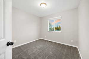 Unfurnished room with dark colored carpet and a textured ceiling