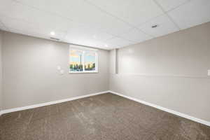 Carpeted spare room with a drop ceiling and recessed lighting