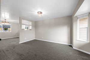 Empty room featuring dark carpet and a textured ceiling