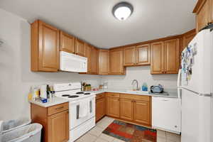 Kitchen with white appliances, light tile patterned floors, and light countertops