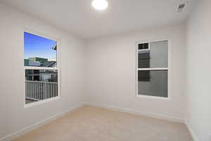 Empty room featuring light colored carpet and baseboards