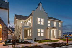 Back of house featuring a balcony, stucco siding, a shingled roof, and a mountain view
