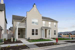 View of front facade featuring a shingled roof, stucco siding, and a balcony