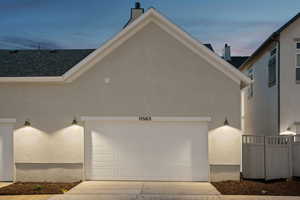 View of home's exterior with stucco siding, driveway, a garage, and a shingled roof