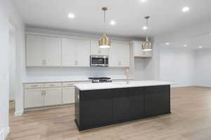 Kitchen with pendant lighting, an island with sink, stainless steel appliances, recessed lighting, and light wood-style flooring