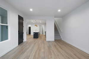 Unfurnished living room with recessed lighting, light wood finished floors, and stairway