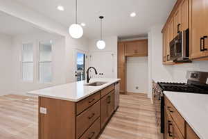 Kitchen featuring stainless steel appliances, brown cabinetry, light wood finished floors, backsplash, and recessed lighting