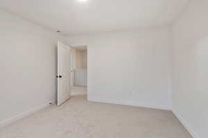 Spare room featuring light colored carpet and baseboards