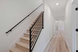 Stairway featuring wood finished floors and recessed lighting