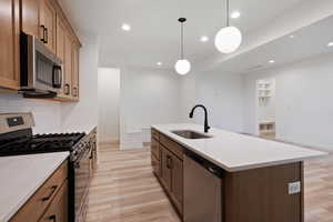 Kitchen with stainless steel appliances, light wood-style floors, recessed lighting, pendant lighting, and decorative backsplash