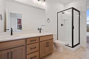 Bathroom featuring double vanity, a shower stall, and light tile patterned floors