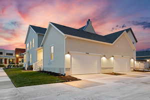 View of front facade featuring a front yard, concrete driveway, stucco siding, a garage, and roof with shingles