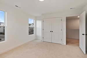 Unfurnished bedroom with light carpet and a closet
