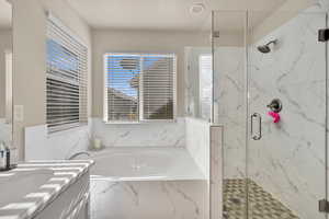 Full bath featuring vanity, a marble finish shower, and a garden tub